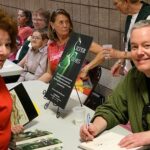 Oz-Stravaganza begins at Chittenango High School! Paul Miles Schneider signs copies of his novel "Silver Shoes" sitting by the MGM Munchkins from "The Wizard of Oz." 92-year-old Karl Slover can be seen at the next table greeting fans.