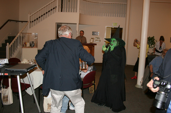 Hamilton Meserve chases after master Wicked Witch impressionist Kurt Raymond with a carafe of water as the startled crowd cheers and laughs.