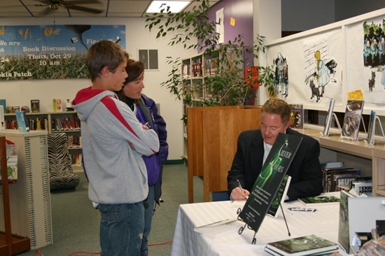 Paul Miles Schneider signs a copy of his book “Silver Shoes” for Gina Spain Gerken and her son Chandler at the Louisburg Library. October 2009.