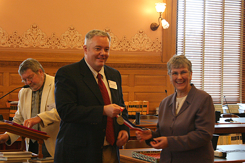 Paul Miles Schneider receives his medal from Jo Budler, the State Librarian of Kansas, as author of “Silver Shoes,” one of the 2010 Kansas Notable Books.