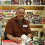 Paul Miles Schneider signs a copy of "The Powder of Life," a sequel to his novel "Silver Shoes," at the Town Crier Bookstore in Emporia, Kansas.