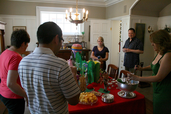 Jane Albright serves punch from a silver bowl (for "Silver Shoes") and other Oz-themed refreshments. An impressive Emerald City throne room display is seen as a centerpiece!